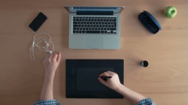Üstten Görünüm Tasarımcısı adam veya Illustrator onun grafik tablet ve dijital tasarım oluşturma dizüstü kullanır ve başparmak sonunda ortaya çıkıyor