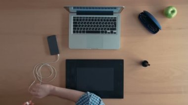 Üstten Görünüm tasarımcı adam veya Illustrator onun grafik tablet ve dijital tasarım oluşturma dizüstü kullanır onun smartphone kulaklık takar ve müzik dinliyor