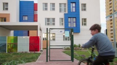 Genç çocuk renkli bina önünde bir bisiklet sürme