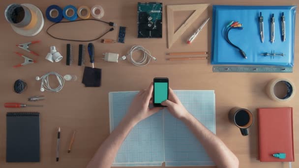 Üstten Görünüm yazılım mühendisi, masanın üstüne ekipman yeşil ekran tam cep telefonu akıllı telefon kullanıyor — Stok video