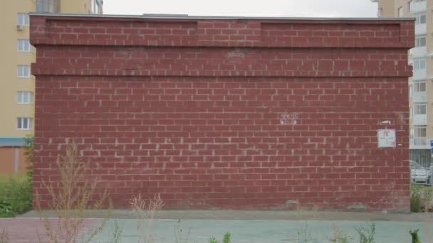 Joven niño montando una bicicleta en frente del colorido edificio — Vídeo de stock