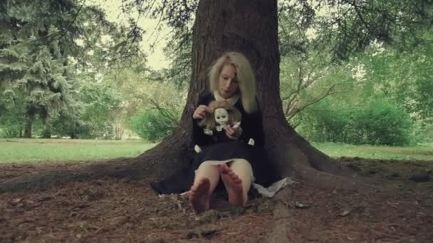 Стилизованный выстрел жуткая белая женщина с куклой в траве в лесу — стоковое видео