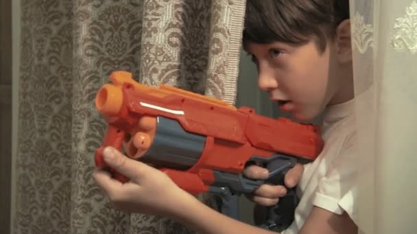 Мальчик играет дома с игрушечным пистолетом — стоковое видео