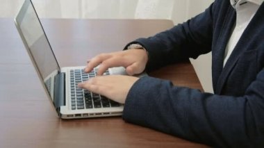 Dizüstü bilgisayar önünde ofisinde çalışan genç işadamı