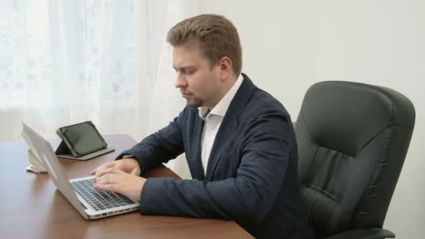 Mladý podnikatel pracuje ve své kanceláři u přenosného počítače. Přenosný počítač nefunguje on je naštvaný a frustrovaný dopadne stůl a jde do okna v hněvu. — Stock video