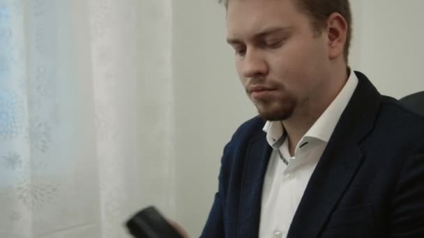 Jeune homme d'affaires faisant des achats en ligne dans son bureau devant l'ordinateur portable prend son portefeuille et compte les factures puis acquiesce contentement hoche la tête — Video