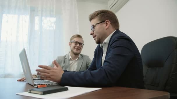 Twee zakenlieden bespreking van hun project achter een laptopcomputer — Stockvideo