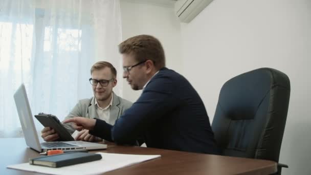 Dos hombres de negocios discutiendo el proyecto de la oficina mirando la pantalla táctil de la tableta digital — Vídeo de stock