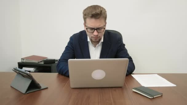 Junger gestresster Geschäftsmann, der in seinem Büro intensiv vor dem Laptop sitzt und auf der Tastatur tippt und viele, viele Briefumschläge mit Briefen in seinen Schreibtisch flattern, ist irritiert — Stockvideo