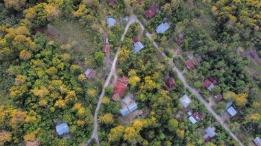 Bu yüksek irtifa drone perspektifi araziyi canlı bir harita olarak gösteriyor. Topraklı tarlaların ve çayırların geometrik desenleri, antik, katmanlı dağların güçlü organik kıvrımlarına karşı keskin bir zıtlık oluşturan desenli bir tuval oluşturur..
