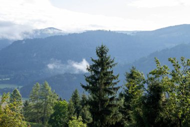 Vistara, Carinthia 'daki Avusturya dağlarının üzerinde. Fotoğraf güneş doğduktan hemen sonra çekildi. Bulutlar vadiden dağlara doğru hareket ediyor..