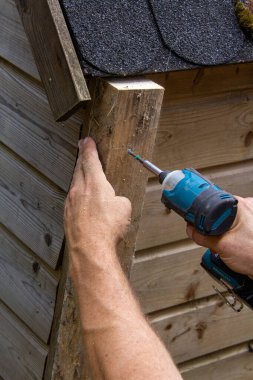 Tamirci, ahşap tavşan evini tornavidayla tamir ediyor..