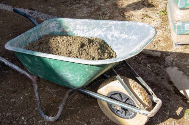 Tuğla duvar örmek için el arabasında çimento.