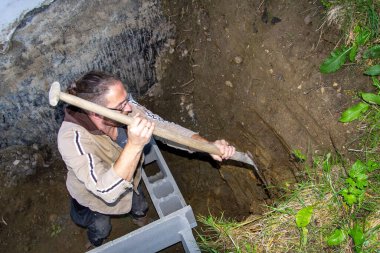 Temel tuğla bir duvar inşa etmek için dağı kazmak. Ev geliştirme genişletiliyor.