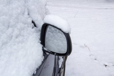 Karla kaplı bir arabanın ayna ve camları. Zorluk ve tehlikeden kaçınmak için sürücünün kalkıştan önce karı kaldırma sorumluluğu vardır..