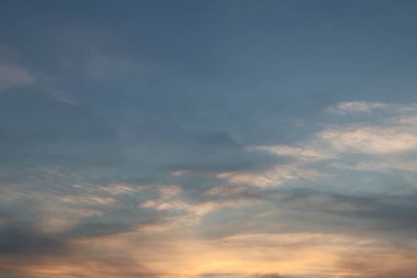 Alacakaranlıkta altın ışıkla aydınlatılan yumuşak sirrus bulutlarıyla güzel gün batımı gökyüzü.