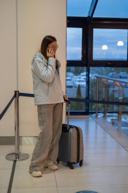 Havaalanının girişine yakın bir yerde elinde bavuluyla duran bir adam. Onlar bir cep telefonuyla konuşuyorlar. Akşam yaklaşırken ortamın gezginleri ve hareketli bir atmosferi var..