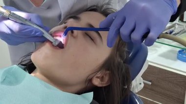 Bir dişçi gün içinde klinikte bir hastaya diş tedavisi uygular. Dişçi dişleriyle uğraşırken hasta bir sandalyede oturur..
