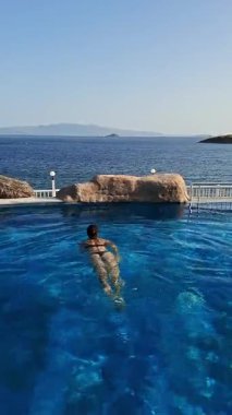 Deniz kenarında serinletici bir içkinin tadını çıkarırken güzel bir sahil bölgesinde havuzda dinleniyorum.