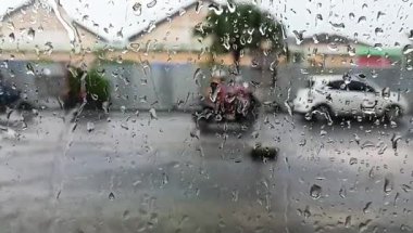 Yağmur damlalarıyla ıslanmış bir pencereden görülen bir yerleşim yeri manzarası