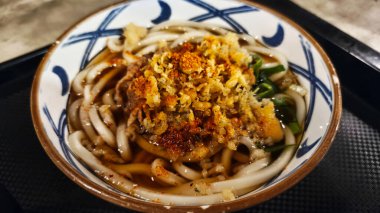 Bir kase udon, bir çeşit kalın Japon buğday eriştesi, sıcak çorba ve çeşitli malzemelerle servis edilir.