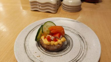 Tabakta çeşitli malzemelerle süslenmiş mini suşi kekleri.