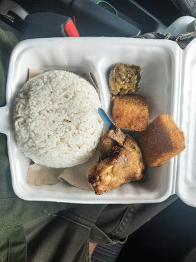 Pirinç tavuğu ve çeşitli mezeler beyaz bir kapta otururlar. Hızlı ve uygun bir yemek seçeneği sunarlar. Belki öğle yemeği ya da akşam yemeği için..