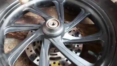 Motosiklet tekerleği taşıyıcısı, garajda bir tekerlek üzerinde çalışan bir tamirciyi aracın sorunsuz çalışmasını ve güvenli bir şekilde ulaşımını sağlayan araçları kullanarak gösteriyor..