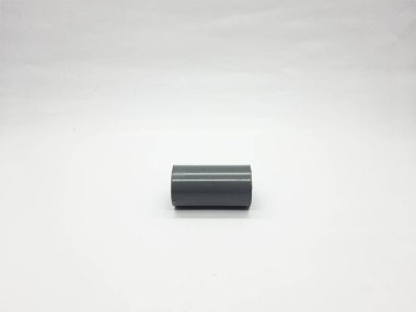Single dark gray pvc pipe coupling rests centered on a stark white background representing a basic plumbing component essential for joining pipes in construction and repair projects.
