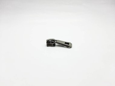 Tek metal fermuar çekme sürgüsü, moda veya tamir gereksinimleri için donanım bileşenlerini temsil eden parlak beyaz bir yüzey üzerinde tek başına dinlenir..