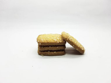 Parlak şeker kristalleri ile tozlanmış altın esmer tereyağlı kurabiyeler temiz beyaz bir zemin üzerine istiflenir ve her durum için cezbedici bir tatlı oluşturur..