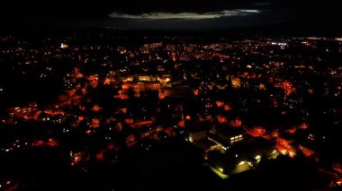 Witness a stunning aerial view of a vibrant and bustling city at night, showcasing its beautiful lights and urban charm