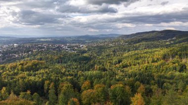 A stunning aerial perspective that showcases vibrant forests, majestic mountains, all beneath beautiful cloudy skies
