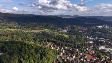 A stunning aerial view of lush forests and charming homes nestled harmoniously within majestic mountains