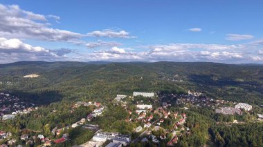 A breathtaking aerial view showcasing the vast, lush green hills and beautiful residential areas in harmony