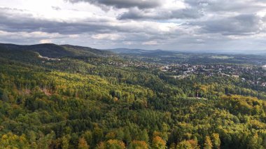A stunning aerial view of vibrant green landscapes and picturesque hills beneath a dynamic, colorful sky