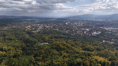 A breathtaking aerial shot elegantly showcasing vibrant, colorful forests along with a picturesque town nestled below