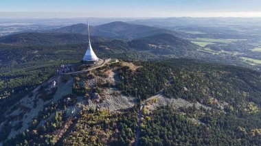 Göz kamaştırıcı hava manzarası görkemli bir dağ zirvesini vurguluyor canlı, yemyeşil ortamda büyük bir yapıyla.