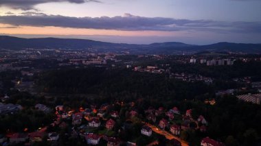 A stunning aerial view captures a sprawling cityscape at sunset, highlighting hills and residential areas