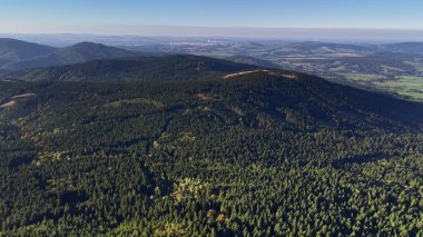 Enjoy a stunning aerial view of lush forests and majestic hills stretching endlessly