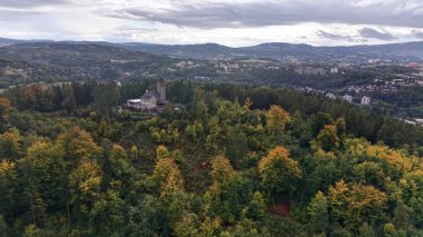 Stunning and breathtaking aerial footage captures a lush green forest that has a historic building nestled within it