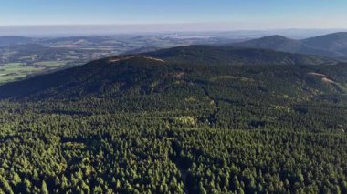 Stunning aerial views that beautifully showcase the vast forests and rolling hills beneath a clear, blue sky