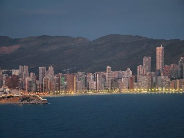 Günbatımı şehir manzarası, alacakaranlıkta parlayan kıyı şeridi, aydınlatılmış sahil manzaralı akşam ufku ve yükseliş