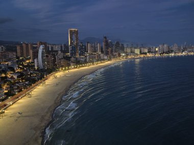 Gece kıyı şeridi parıltısı, yıldızlı gökyüzünün altında sessiz okyanus manzarası parlak kıyı şeridi ve şehir silueti