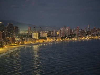 Alacakaranlıkta geniş bir kıyı şeridi, alacakaranlıkta engin kıyı manzarası aydınlık gezinti güvertesi ve sakin sörf ile