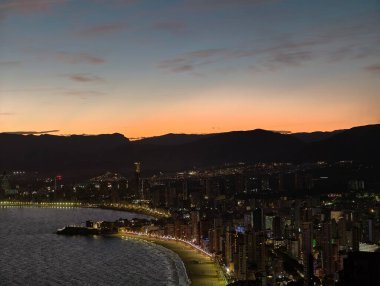 Huzurlu bir alacakaranlık gökyüzünü ve suyu resmeder. Şehir manzarasının üzerindeki yumuşatıcı pastel gölgelerle.