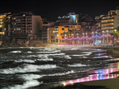 Canlı kentsel ufuk çizgisi sakin suları renkli yansımalar ve canlı atmosferle aydınlatıyor.