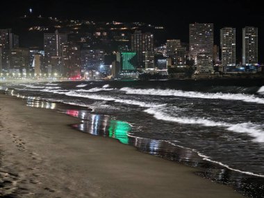 Canlı kentsel ufuk çizgisi sakin suları renkli yansımalar ve canlı atmosferle aydınlatıyor.