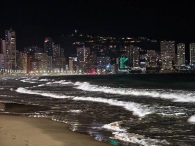 Canlı kentsel ufuk çizgisi sakin suları renkli yansımalar ve canlı atmosferle aydınlatıyor.