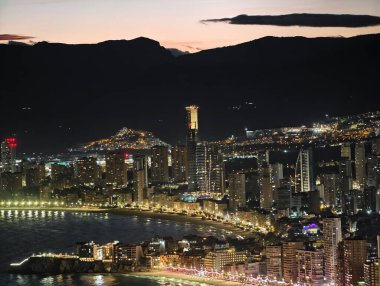 Canlı kentsel ufuk çizgisi sakin suları renkli yansımalar ve canlı atmosferle aydınlatıyor.